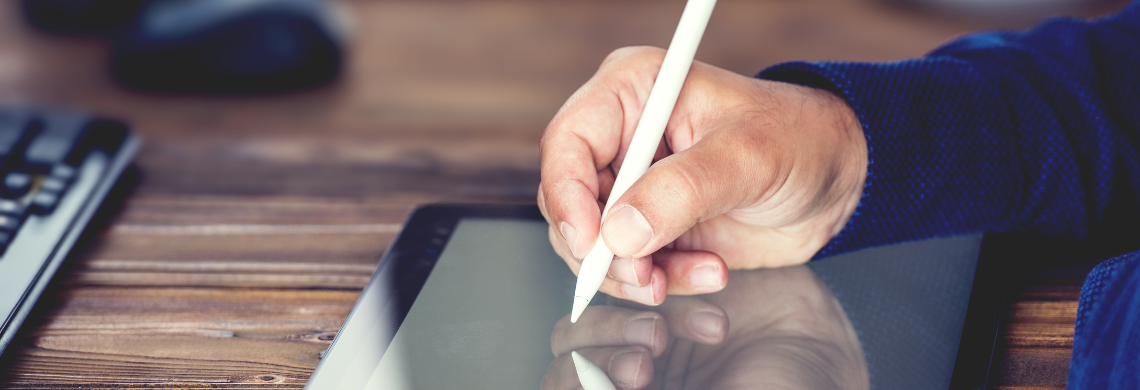 Person schreibt mit Stift auf ein Tablet